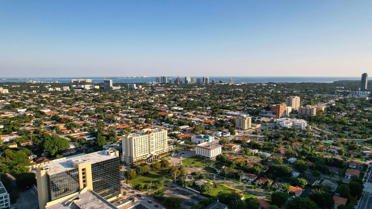Aerial view of a sprawling cityscape with dense neighborhoods and buildings under a clear sky.